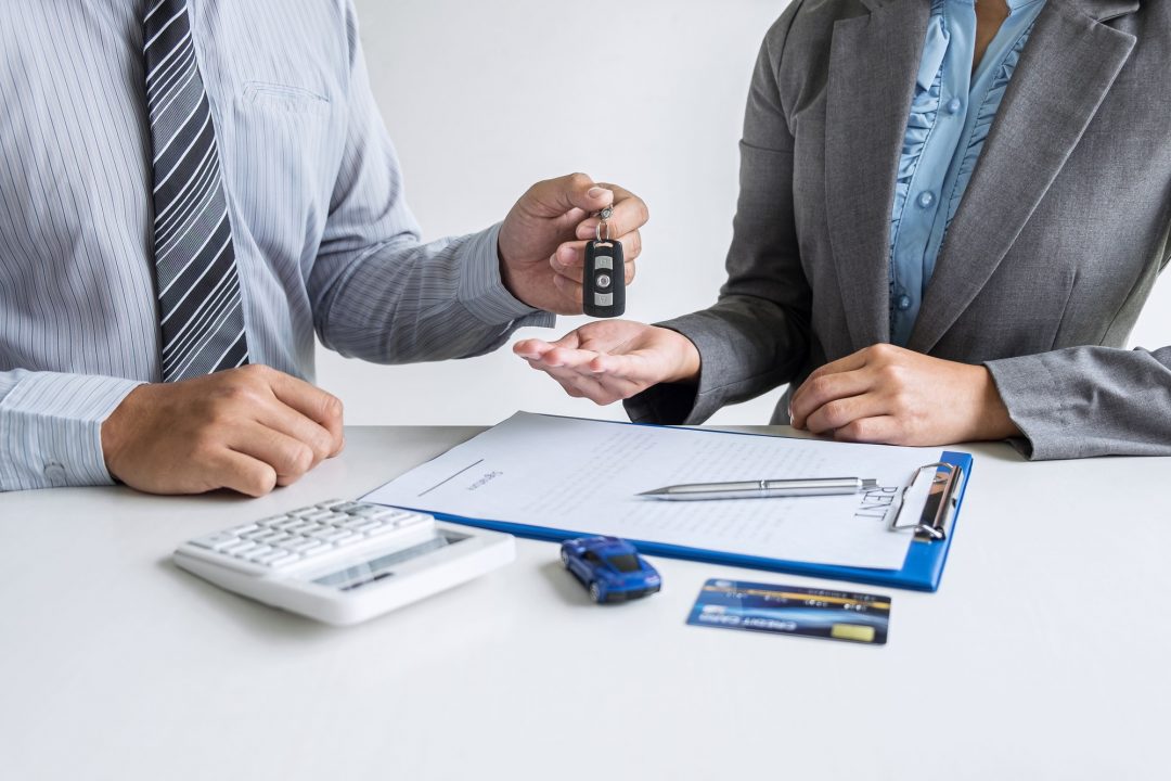 car rent agent manager holding key of new car giving to woman client after signing good deal